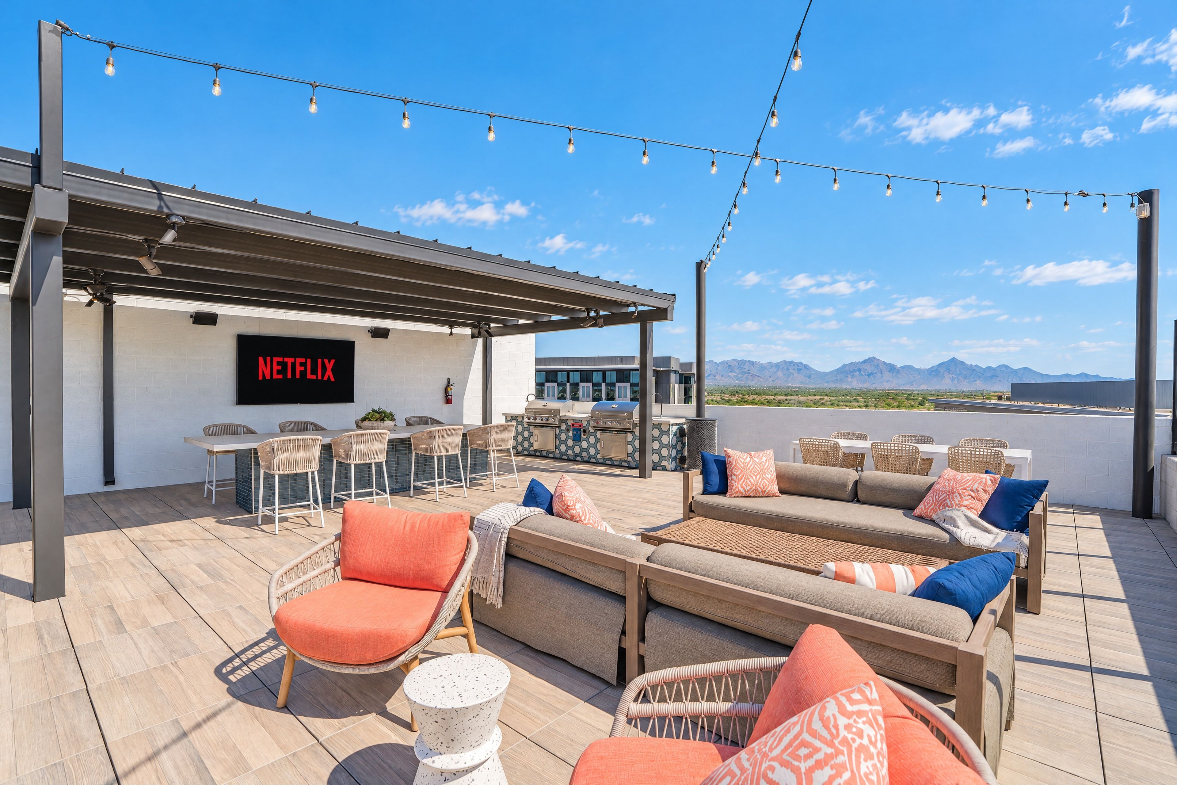 Terraza en la azotea con mobiliario exterior, letrero de Netflix y vistas a las montañas.