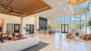 Eine geräumige Hotelhalle mit hoher Decke, einer Rezeption, Sitzbereichen und großen Fenstern mit Blick ins Freie.