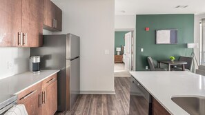 A modern kitchen with stainless steel appliances, wooden cabinets, and a white countertop. - Landing | Spectacular 2BD, Gym (Birmingham)