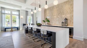 A modern kitchen with a marble countertop, bar stools, pendant lights, and a tiled backsplash. - Landing | Modern 1BD in Whitestone (Fort Worth)