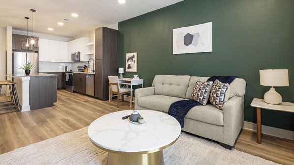 Ein modernes Wohnzimmer mit einer Couch, einem Couchtisch und einer Küche im Hintergrund.