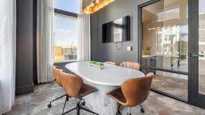 A conference room with a round table, leather chairs, a flat-screen TV, and a view of the outdoors. - Landing | Modern 1BD in Whitestone (Fort Worth)
