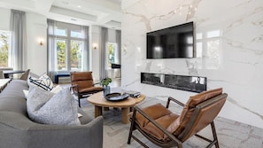 A modern living room with a fireplace, leather chairs, a sofa, and a flat-screen TV mounted on the wall. - Landing | Modern 1BD in Whitestone (Fort Worth)