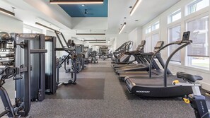 Ein Fitnessstudio mit Laufbändern, Kraftgeräten und Kurzhanteln.