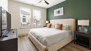 A bedroom with a bed, a desk, a TV, a ceiling fan, and a window with blinds. - Landing | Incredible 1BD in Whitestone (Fort Worth)