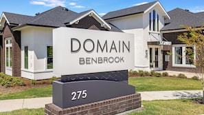 Une enseigne pour le domaine Benbrook, de style architectural moderne, avec une entrée imposante et une pelouse bien entretenue.