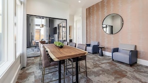 A modern interior with a wooden dining table, leather chairs, a round mirror, and a patterned wall. - Landing | Modern 1BD in Whitestone (Fort Worth)