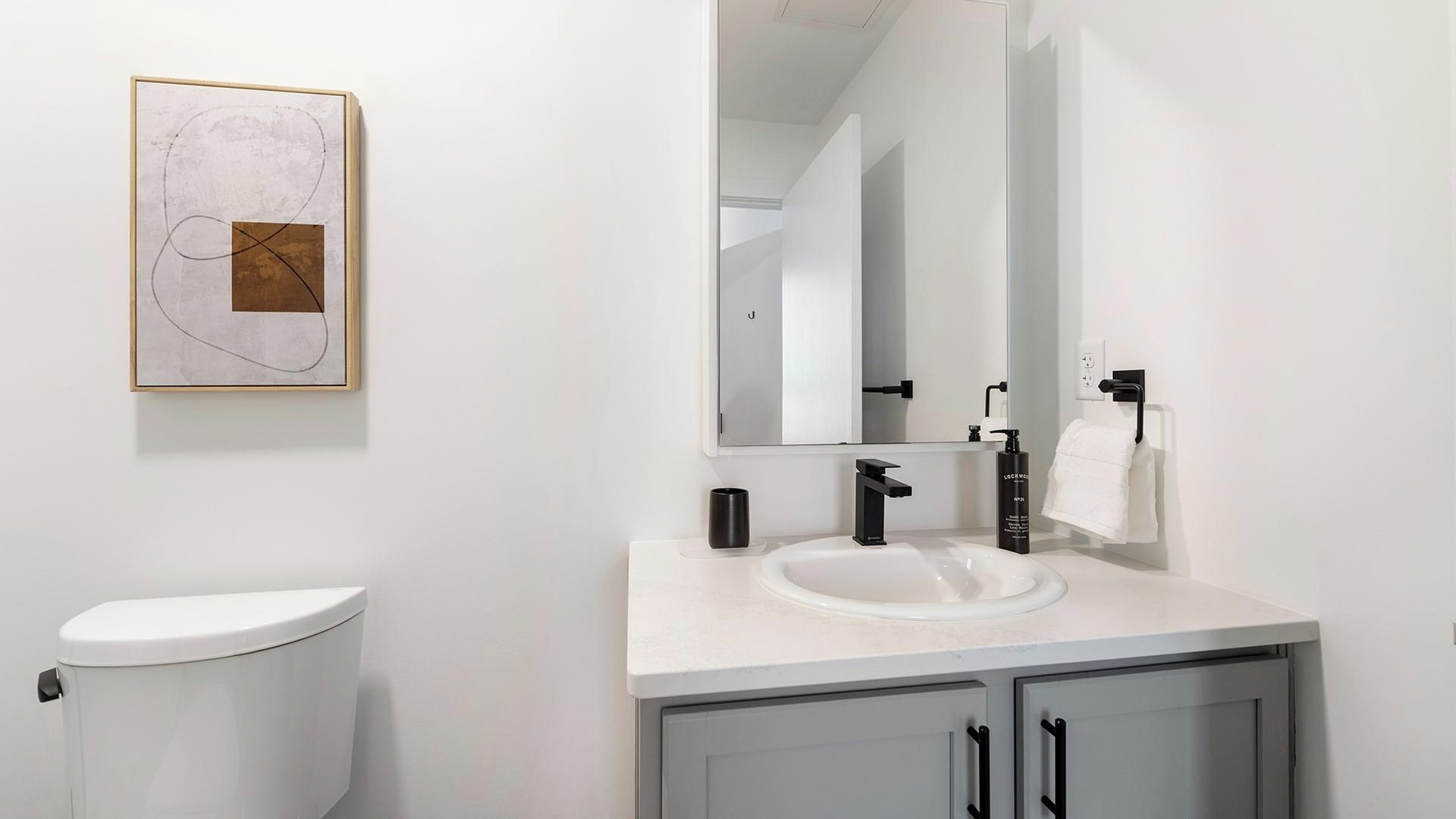 A modern bathroom with a toilet, sink, and cabinet.