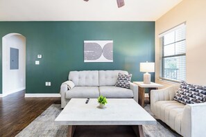 A living room with a grey sofa, a white coffee table, and a patterned armchair. - Landing | Spectacular 2BD, Pool, Gym (Oxford)