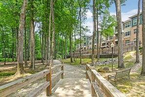 A wooden bridge leading to a building with multiple floors, surrounded by trees. - Landing | Spectacular 2BD, Pool, Gym (Oxford)