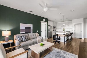 Ein modernes Wohnzimmer mit einer Couch, einem Couchtisch und einem Essbereich mit Stühlen.