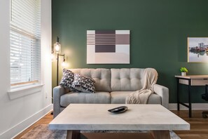 A modern living room with a sofa, a coffee table, a lamp, and artwork on the wall. - Landing | Modern 1BD, Gym (Pensacola)