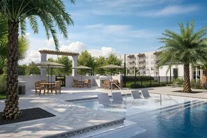 A pool area with lounge chairs, a barbecue setup, and outdoor seating. - Landing | Modern 2BD, Gym (Pensacola)