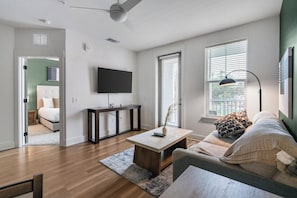 A modern living room with a sofa, coffee table, and a TV mounted on the wall. - Landing | Stylish 1BD, Gym (Pensacola)