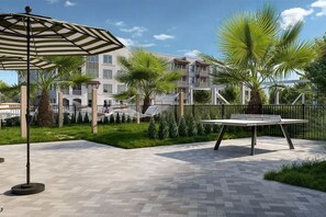 A paved outdoor area with a hammock, a table, and an umbrella. - Landing | Stylish 1BD, Gym (Pensacola)