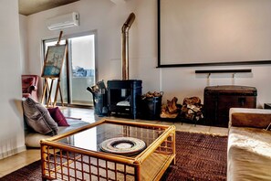 A living room with a glass coffee table, a sofa, a fireplace, a painting on the wall, and a large window. - Stylish 3BR w/ Huge Veranda and City View, Nicosia (Nicosia)