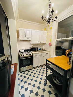 A kitchen with white cabinets, a gas stove, a microwave, and a black and white tiled floor. - Comfortable, Super Clean & Close to NYC (Hoboken)
