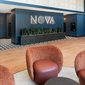 A reception area with a 'NOVA' sign, patterned chairs, and a checkered floor. - Landing | Stunning 1BD, Yoga Studio, Pool (Green Bay)