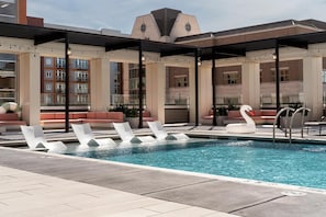 A rooftop pool area with lounge chairs, a swan float, and a covered seating area. - Landing | Stunning 1BD, Yoga Studio, Pool (Green Bay)