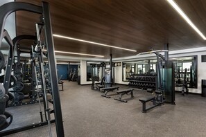 Ein modernes Fitnessstudio mit Kraftgeräten, Laufbändern und einer Spiegelwand.