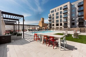 Een zwembadterras met een zwembad, zitplaatsen en een pergola.
