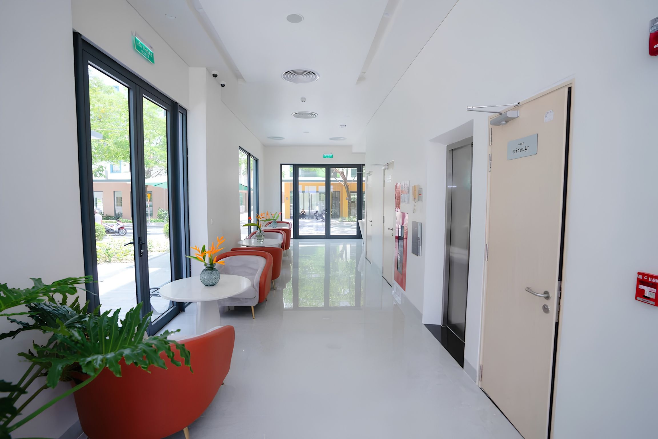 A modern hallway with a dining area, large windows, and a door with a sign.