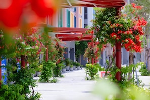 A covered walkway with potted plants and red flowers.
