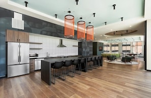 A modern kitchen with a central island, bar stools, and pendant lighting. - Landing | Modern 1BD, Pool, Yoga Studio (Green Bay)