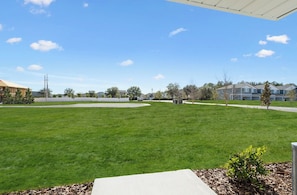 A residential area with a well-maintained lawn, a clear sky, and houses in the background. - Landing | Modern 3BD, Clubhouse, Pool (Jacksonville)