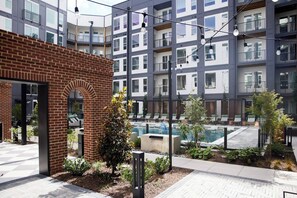 A modern building with a brick facade, a pool area, and a landscaped garden. - Landing | Beautiful 1BD, Rooftop Lounge (Richmond)