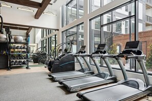 A gym with multiple treadmills, weight machines, and a variety of weights. - Landing | Chic 1BD, Rooftop Lounge (Richmond)