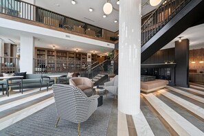 Um hall amplo com teto alto, escada e área de biblioteca.