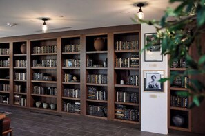 A library with multiple wooden bookshelves filled with books and decorative items. - Landing | Chic 2BD, Rooftop Lounge (Richmond)