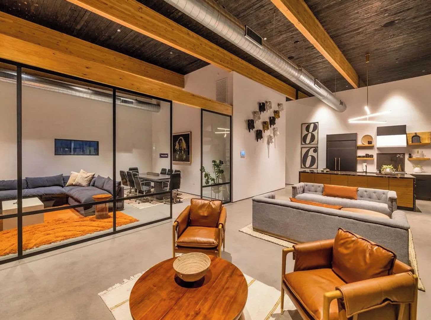 A modern interior with a dining area, sofas, and a kitchen.