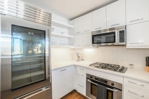 Een moderne keuken met witte kasten, roestvrijstalen apparatuur en een betegelde achterwand.