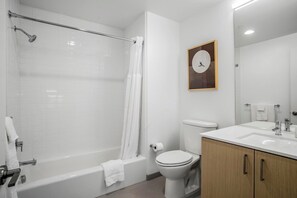 A modern bathroom with a bathtub, shower, toilet, and a sink with a mirror. - Landing | Stylish 2BD, Gym, Pool (Roy)