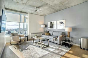 A modern living room with a sofa, armchair, coffee table, and floor lamp. - Landing | Stylish 2BD, Gym, Pool (Roy)