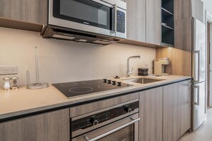 Eine moderne Küche mit eingebauter Mikrowelle, Herd, Backofen und einem Edelstahl-Kühlschrank.