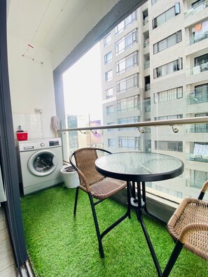A balcony with a washing machine, a table, and two wicker chairs. - Cozy 1-bedroom apartment with AC in lovely Nairobi (Nairobi)