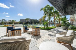 An outdoor seating area with wicker furniture and a pool in the background. - Landing | Beautiful 2BD, Pool (Tampa)