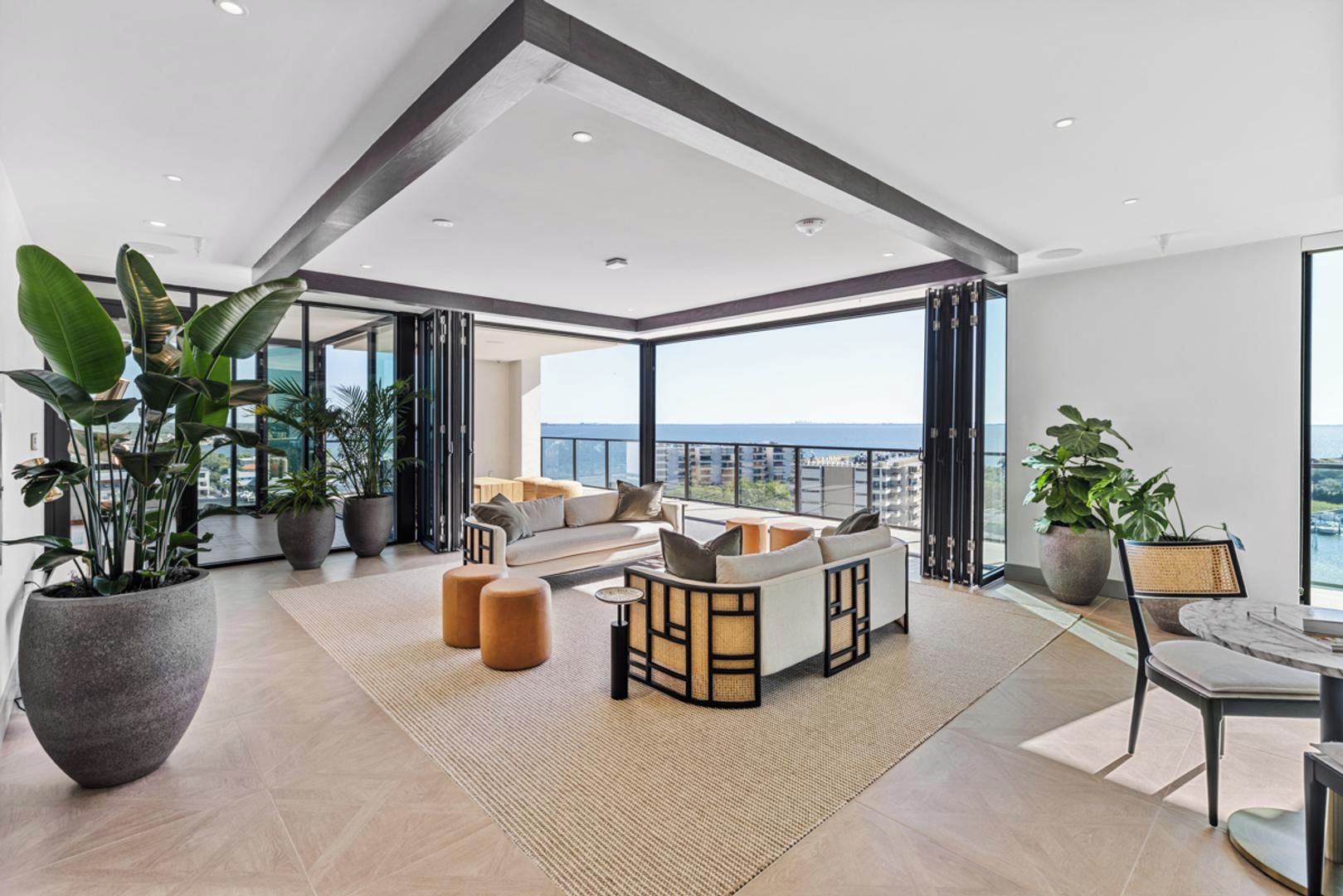 A spacious living area with a sofa set, a dining table, and large potted plants.