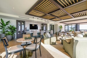 Ein modernes Wohnzimmer mit Esstisch, Sofas und einer Küche im Hintergrund.
