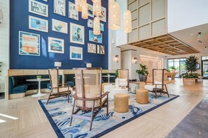 A spacious lobby with a blue wall adorned with framed artwork, wicker furniture, and a large wooden ceiling. - Landing | Spectacular 2BD, Pool (Tampa)