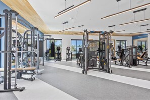 A modern gym with various exercise equipment, large windows, and a clean, spacious layout. - Landing | Modern 1BD, Pool (Tampa)