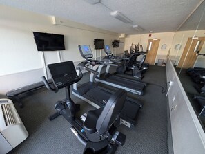 Un centre de remise en forme équipé de tapis de course, de vélos elliptiques et d’un vélo d’appartement.