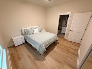 A bedroom with a bed, nightstand, and a door leading to a bathroom. - Bay St. Louis Coastal Getaway. 3BR/3BA Near Old Town (Bay St. Louis)