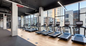 Ein Fitnessstudio mit Laufbändern und Trainingsgeräten, großen Fenstern und modernem Industriedesign.