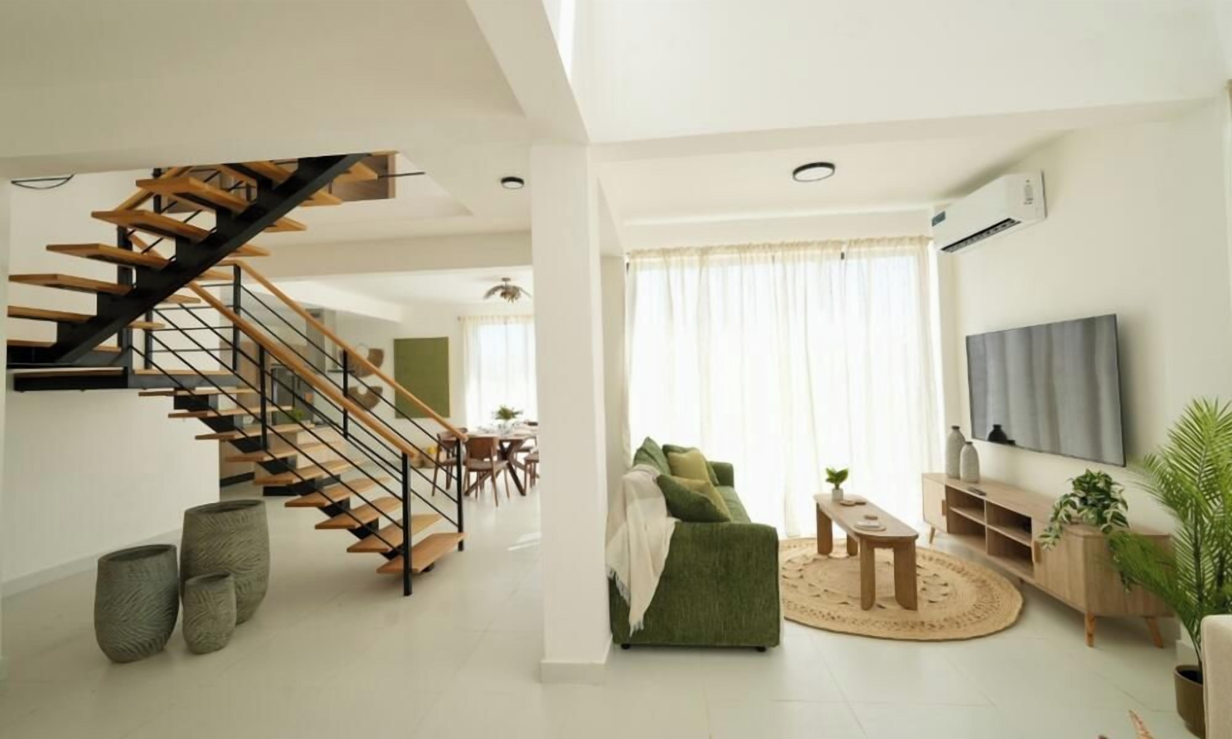 Een moderne woonkamer met een trap, een flatscreen televisie en een eethoek.