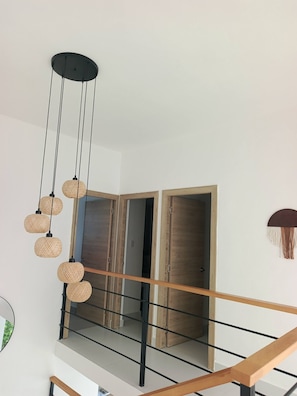 A modern interior with a staircase, wooden doors, and a hanging light fixture. - Paradise Private Pool Villa (Punta Cana)