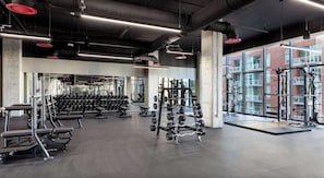 Ein Fitnessstudio mit Gewichte, Bänken und einer Spiegelwand.